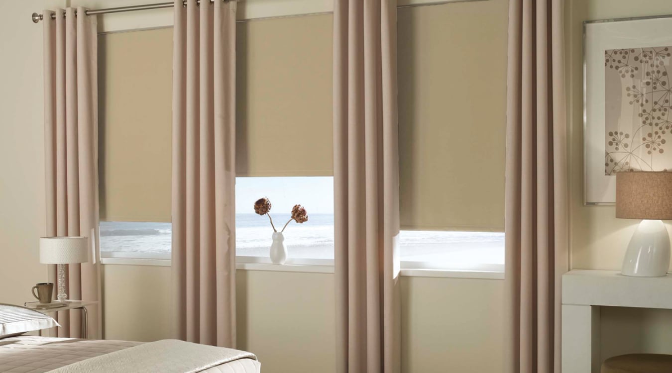 Blackout roller shades layered with curtain